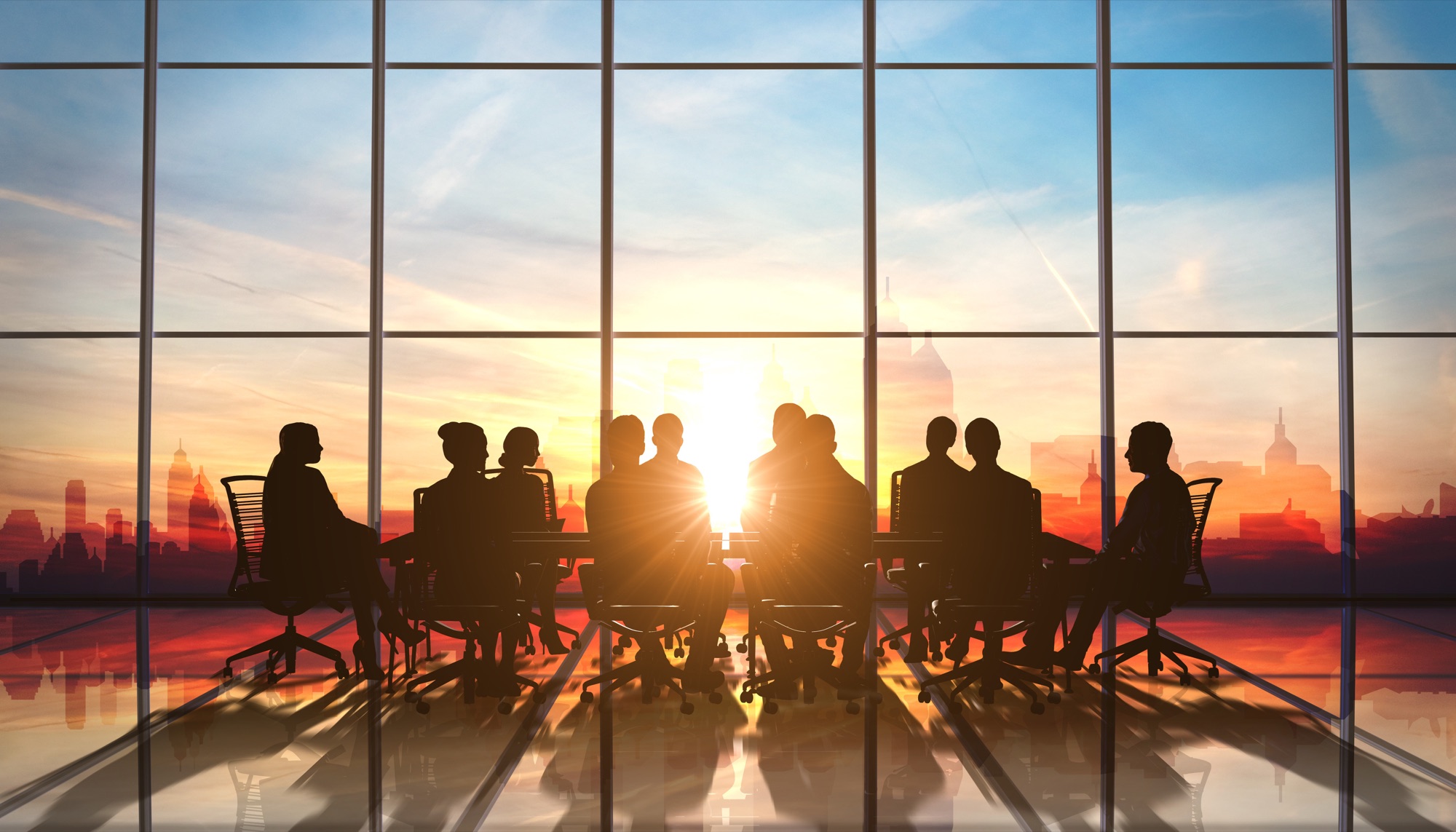A board meeting in silhouette against a city skyline at sunset.